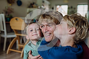 Two sons kissing father's cheeks. Concept of Father's Day, and fatherly love.