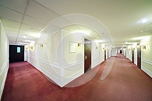 Two spacious light hallways with many wooden doors