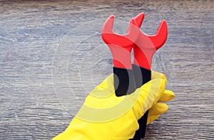 Two spanners in hand in a yellow glove on a wooden background, top view, space for text