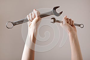 Two spanners in the women`s hands. hands holds a wrenches on a gray background. Combination wrench. big chrome vanadium spanner i