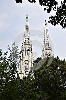 Two spiers, of a gottiga church, located near the atule museum of the famous father of spicoanalysis in Vienna, are framed by tree