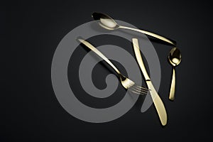 Two spoons, knife and fork on dark background