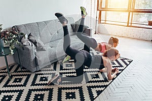 Two sportive female friends doing toning exercise performing donkey kicks at home