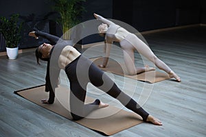Two sportive women doing stretching in plank pose, stretch hands and legs, healthy workout