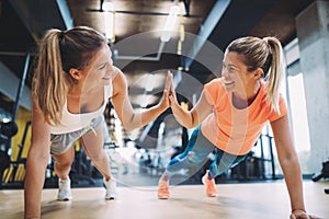 Two sporty girls doing push ups in gym