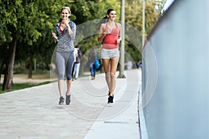 Two sporty women jogging in city