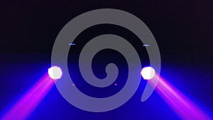 Two spotlights of purple color on the ceiling of the techno club blink and rotate