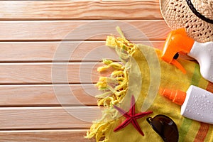 Two spray suncream with hat and sunglasses on wooden slats
