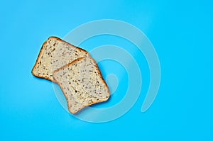 Two square pieces of bread with seeds for toast lies on blue table on kitchen. Top view