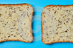 Two square pieces of bread with seeds for toast lies on blue table on kitchen. Top view