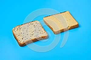 Two square pieces of bread with seeds and vanilla for toast lies on blue table on kitchen