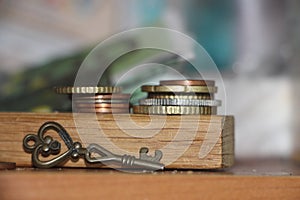 Two Stacks of coins and a key on a wooden background with reflection. Key to profit secret of money gain business concept