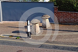 Two staddle stones stand beside the road in a Devon village and act to stop cars driving on the pavement to avoid the adjacent