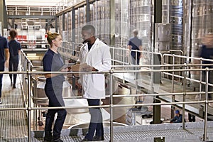 Two staff talking in a modern winemaking factory, close up