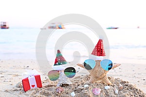 Two starfish on sea beach with sunglasses and santa hat for Merry Christmas and New Years