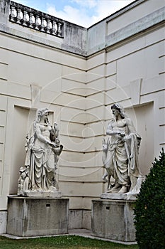 Two statues, a man and a woman, seem to look at each other as if they were talking, in a corner of a garden in Vienna.