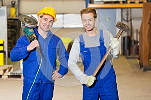 Two steel construction workers posing with angle grinder and ham