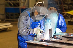 Two steel construction workers welding metal