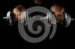 Two steel typesetting dumbbells in male hands, sports backdrop photo