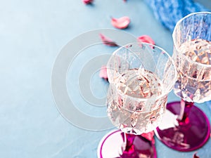 Two stemmed glasses with champagne on blue