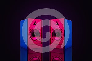 Two stereo speakers with neon light on dark background