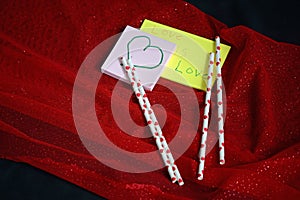 Two sticky notes and hearts on straw.