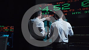 Two stock brokers in front of live market feed