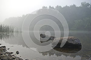 Two stones in the river at the coast in fog