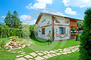 Two-storey country house in a rustic style stands in the summer garden