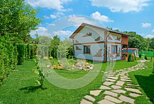 Two-storey country house in a rustic style stands in the summer garden