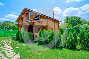 Two-storey country house in a rustic style stands in the summer garden