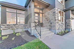 Two storey home facade with stone brick wall and glass paned gray front door