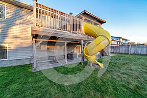 Two storey home with yellow slide on the deck going down to the spacious yard