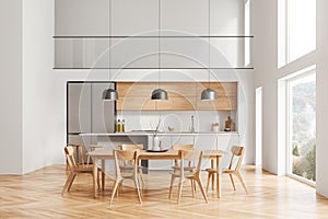 Two storey white kitchen interior with island and table