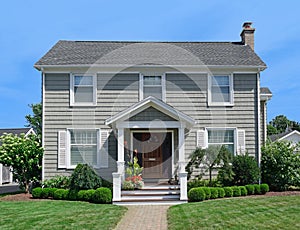 Two story clapboard house with shrubbery and front lawn in summer