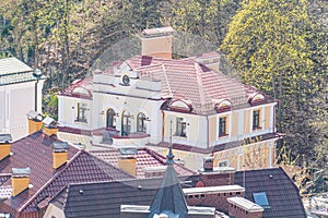 A two-story European building with a red tiled roof, white accents, and classical architectural elements, set against a clear sky photo