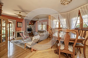 Two-story living room in a house with wooden furniture, a classic wooden dining table with matching chairs, fabric-upholstered