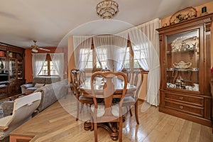 Two-story living room in a house with wooden furniture, a classic wooden dining table with matching chairs, and varnished oak