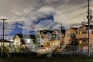 Two story suburban houses on quiet street under clouds at night