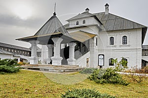 a two-story white monastery building with a wooden roof