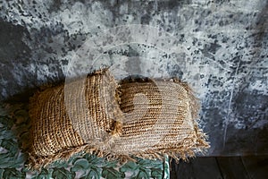 Two straw pillows decoration in trendy loft interior. Gray concrete cement wall