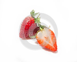 Two strawberries, one half and the whole one behind it is isolated on a white background