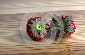 Two strawberries on a wooden shelf