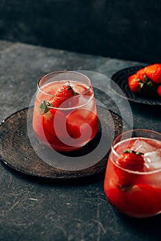 Two strawberry cocktail with ice on dark background