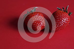Two strawberry on red background