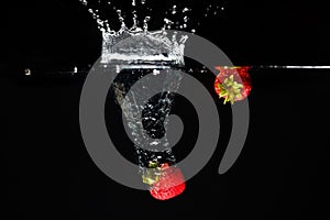 Two strawberrys splashing into water