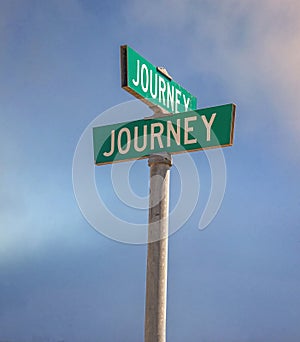 Two street signs indicating the intersection of Journey and Journey Streets with blue sky and light clouds