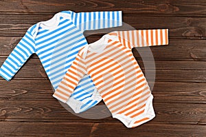 Two striped baby bodysuits on wooden background photo
