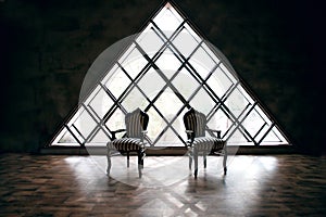 Two striped chairs, black and white, against a background of a triangular window, empty loft, stylish look