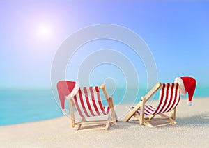 Two striped sunloungers with Christmas Santa hats at ocean sunset beach photo